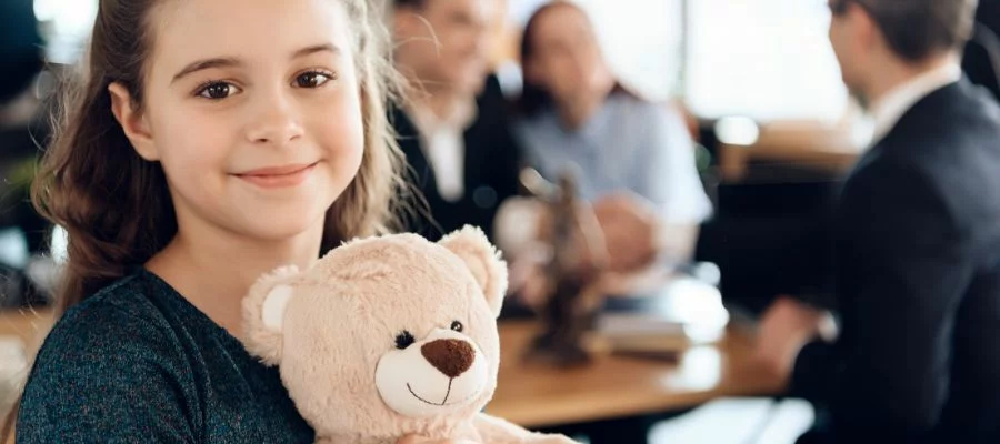 child smiling holding a teddy bear in front of parents