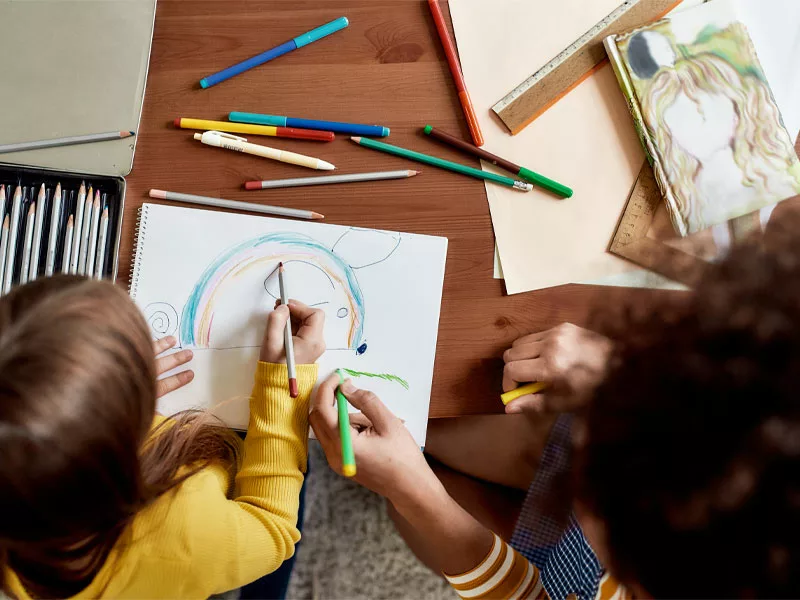two children sitting down drawing together