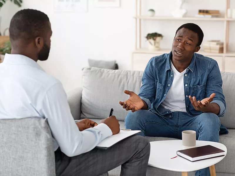 male therapist sitting down talking with a male patient